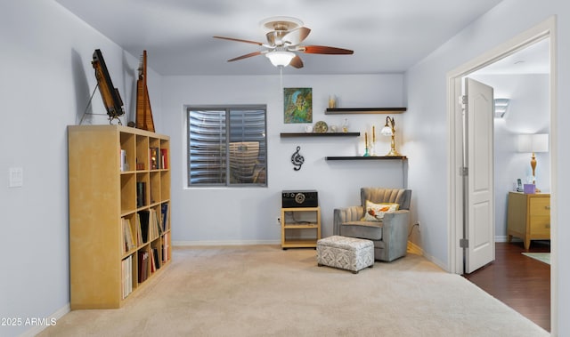 living area with ceiling fan and carpet