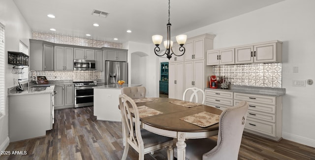 dining area featuring sink, an inviting chandelier, and dark hardwood / wood-style flooring