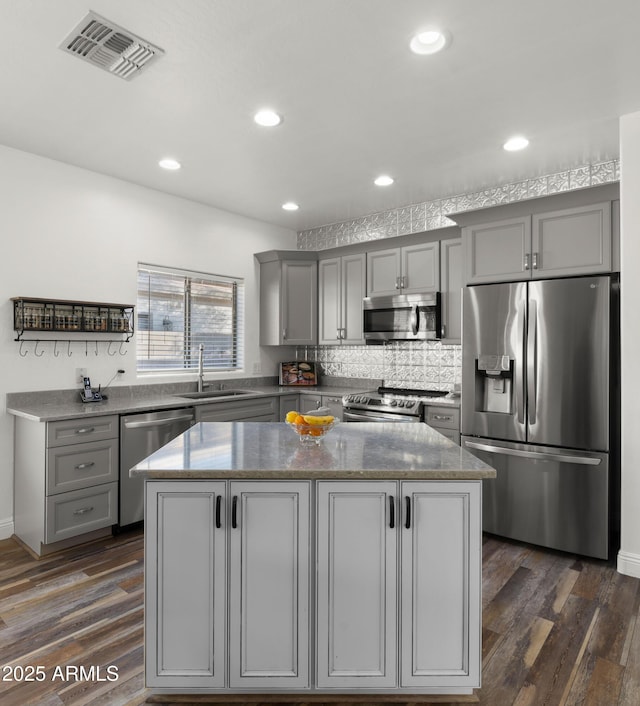 kitchen with sink, gray cabinetry, dark hardwood / wood-style floors, a kitchen island, and stainless steel appliances