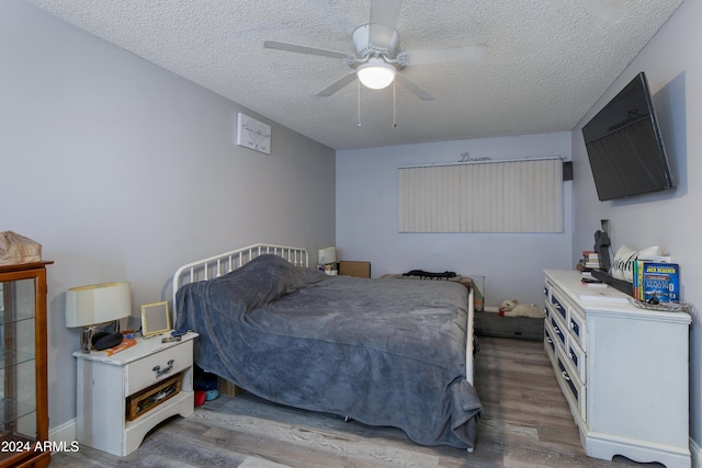 bedroom featuring ceiling fan, light wood-type flooring, and a textured ceiling