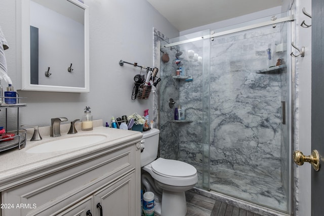 bathroom with vanity, toilet, and a shower with door