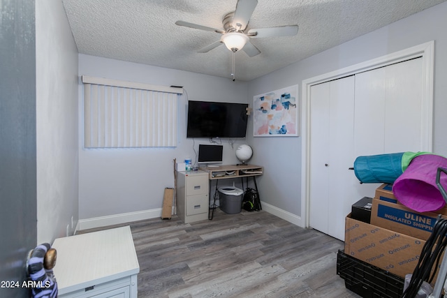 home office featuring a textured ceiling, light wood-type flooring, and ceiling fan