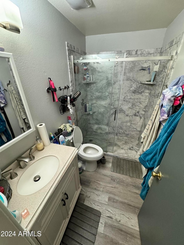 bathroom featuring vanity, hardwood / wood-style flooring, toilet, and a shower with shower door