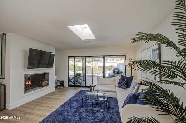 living room featuring a skylight and light hardwood / wood-style flooring