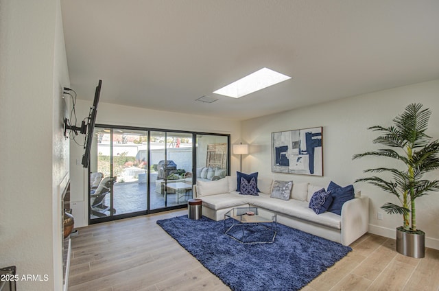 living room with a skylight and light hardwood / wood-style flooring
