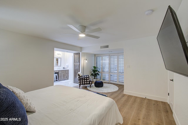 bedroom with ceiling fan, ensuite bathroom, and light hardwood / wood-style flooring
