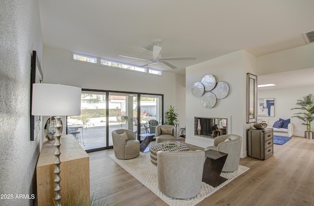 living room with light hardwood / wood-style flooring, ceiling fan, and a multi sided fireplace