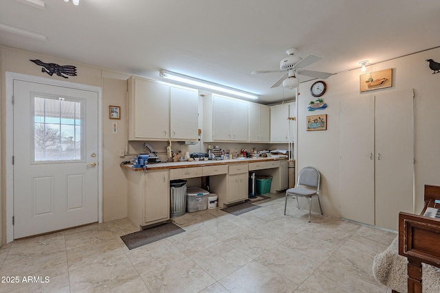 interior space with ceiling fan and white cabinets