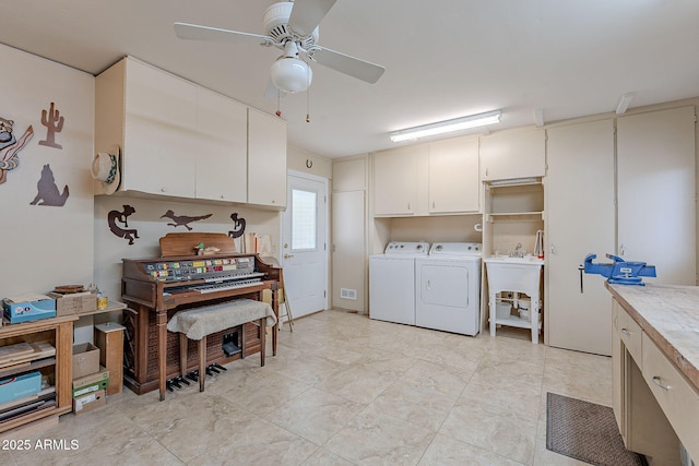 clothes washing area featuring cabinets, ceiling fan, washer and clothes dryer, and a workshop area