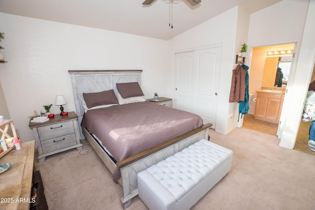 bedroom featuring ensuite bathroom, vaulted ceiling, light carpet, a closet, and ceiling fan