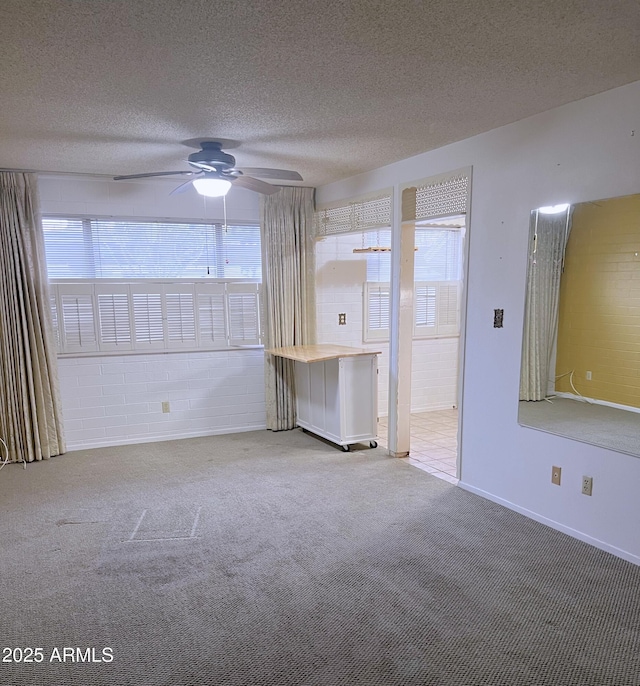 unfurnished room featuring ceiling fan, carpet floors, and a textured ceiling