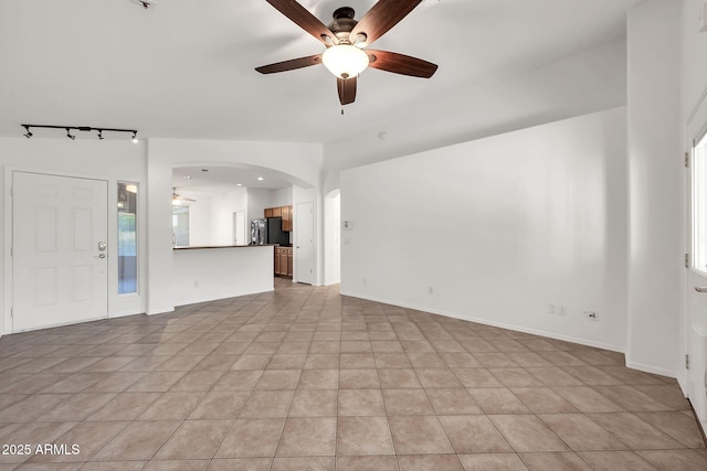 8009 W Salter Dr, Peoria, AZ 85382 - unfurnished living room featuring a ceiling fan, rail lighting, light tile patterned floors, and arched walkways