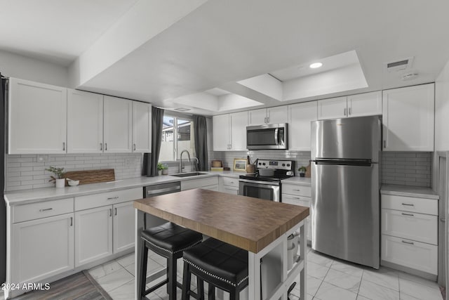 kitchen with decorative backsplash, sink, white cabinetry, and stainless steel appliances