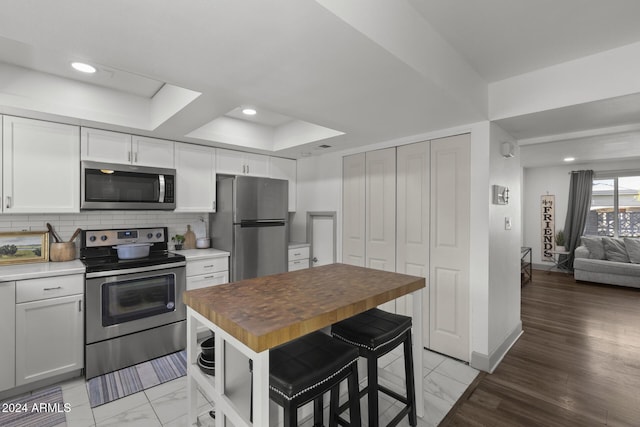 kitchen featuring wood counters, light hardwood / wood-style floors, white cabinetry, and stainless steel appliances