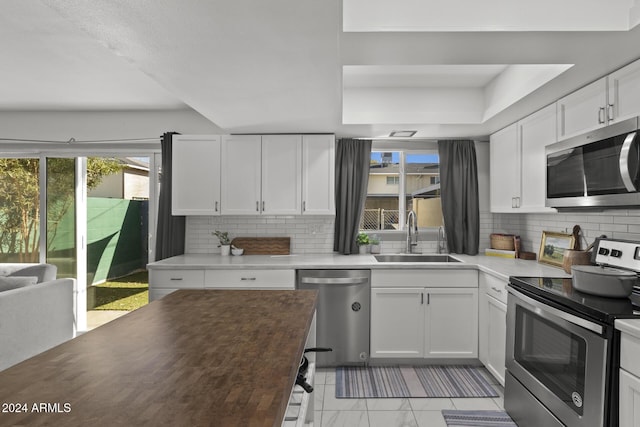 kitchen featuring tasteful backsplash, sink, white cabinets, and stainless steel appliances