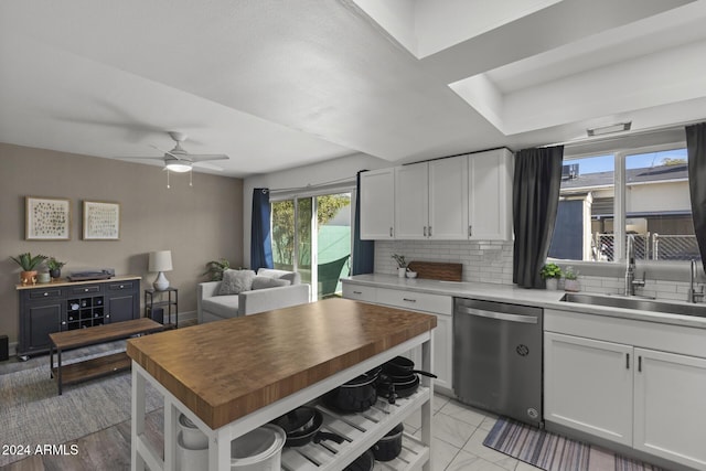 kitchen featuring tasteful backsplash, stainless steel dishwasher, sink, butcher block countertops, and white cabinetry