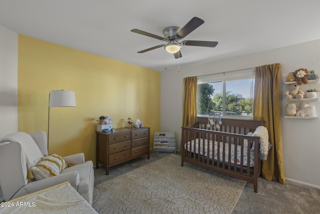 carpeted bedroom featuring a crib and ceiling fan