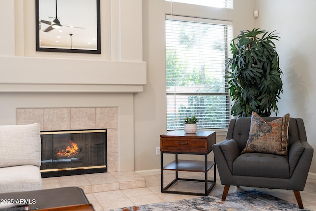 sitting room with baseboards, a ceiling fan, a healthy amount of sunlight, and a tile fireplace