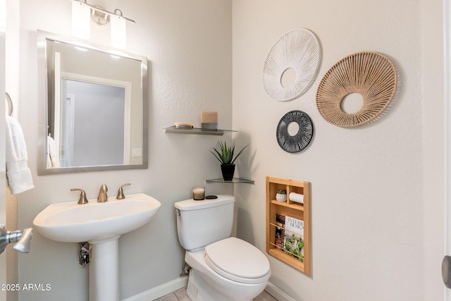 half bathroom featuring baseboards and toilet