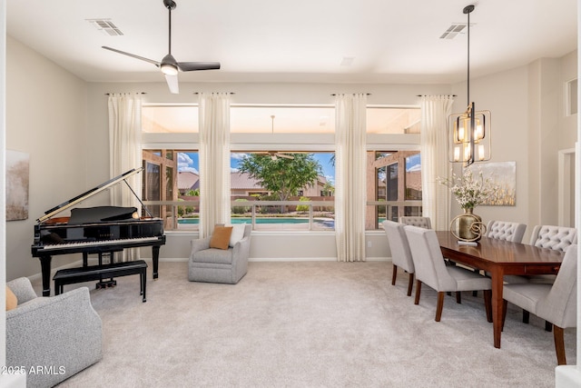 sitting room with visible vents, baseboards, ceiling fan with notable chandelier, and light carpet
