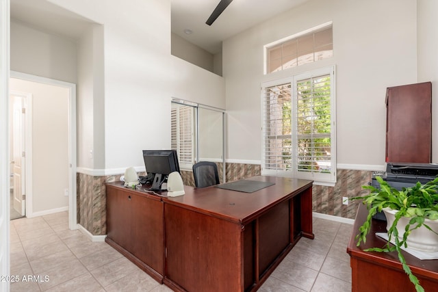 office area featuring baseboards, wainscoting, a towering ceiling, and light tile patterned floors