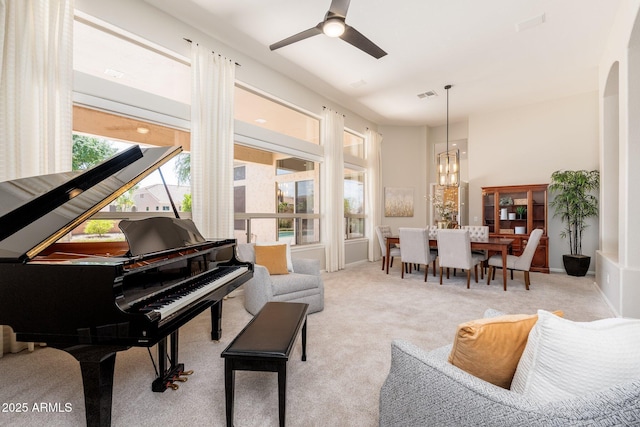 living area with visible vents, carpet flooring, and ceiling fan with notable chandelier