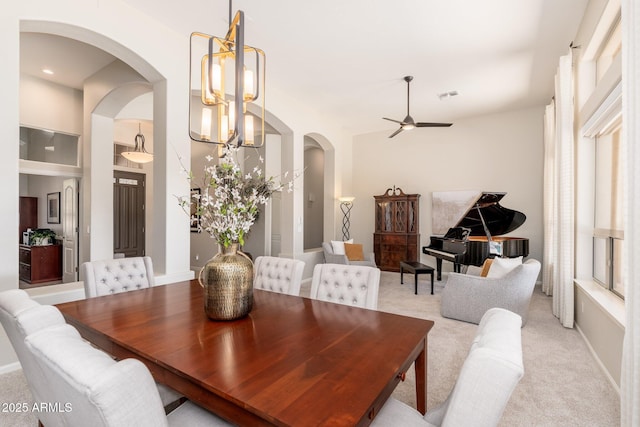 dining room featuring visible vents, arched walkways, a ceiling fan, and light colored carpet
