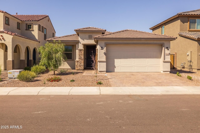 view of front of property featuring an attached garage, stucco siding, a tile roof, and decorative driveway