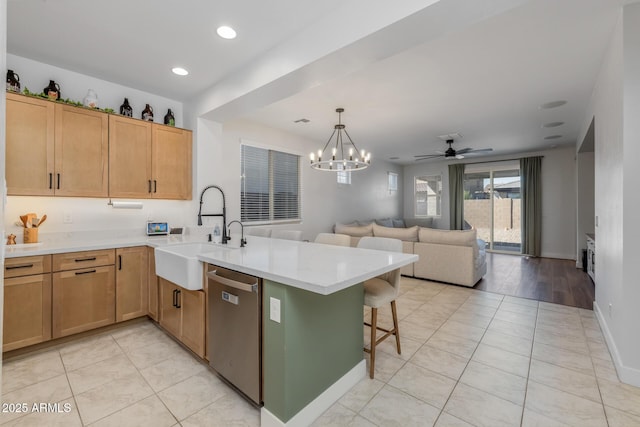 kitchen featuring a sink, stainless steel dishwasher, light tile patterned flooring, and a peninsula