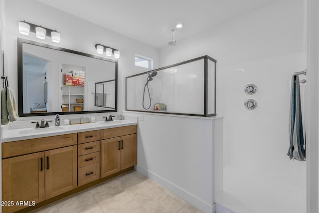 bathroom with a walk in shower, double vanity, and a sink