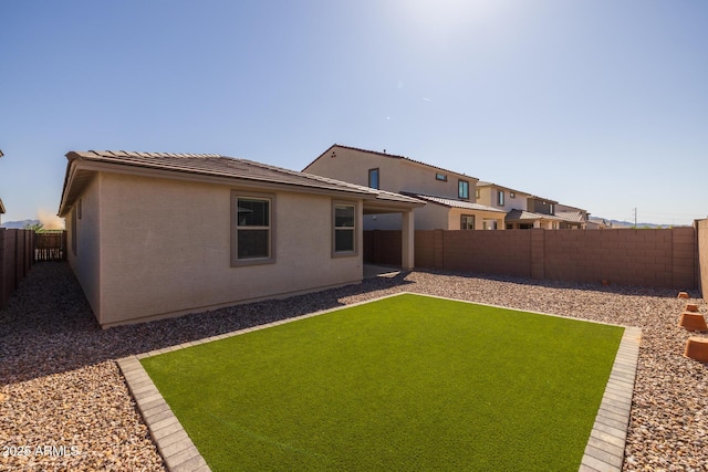 rear view of house with a fenced backyard, stucco siding, and a tile roof