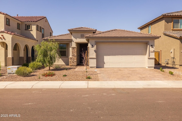 view of front facade with stucco siding, decorative driveway, an attached garage, and a tile roof