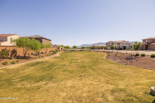view of yard featuring a mountain view, fence, and a residential view