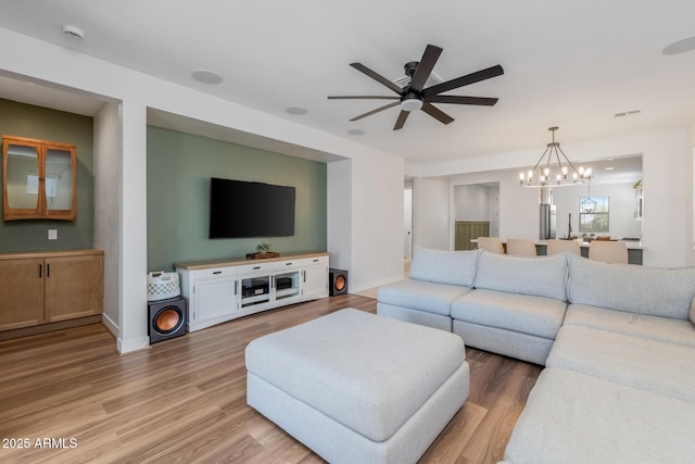 living area with light wood-style flooring, ceiling fan with notable chandelier, baseboards, and visible vents