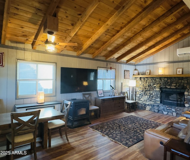 living room with a wood stove, ceiling fan, beamed ceiling, wood-type flooring, and wood ceiling