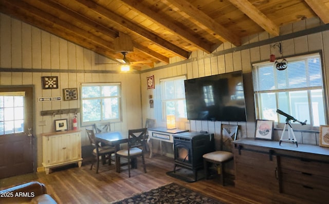 living room featuring a wood stove, ceiling fan, vaulted ceiling with beams, dark hardwood / wood-style flooring, and wood ceiling