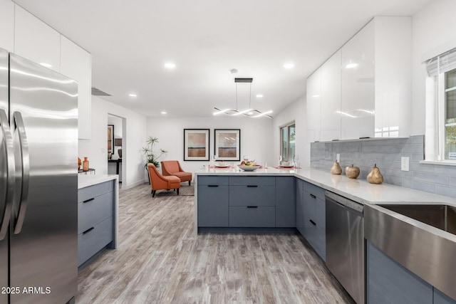 kitchen featuring light hardwood / wood-style flooring, decorative light fixtures, white cabinets, gray cabinets, and stainless steel appliances