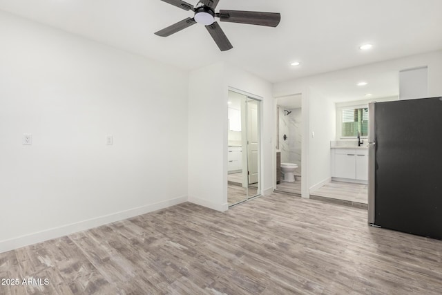 unfurnished bedroom with light hardwood / wood-style floors, stainless steel fridge, a closet, ceiling fan, and ensuite bathroom