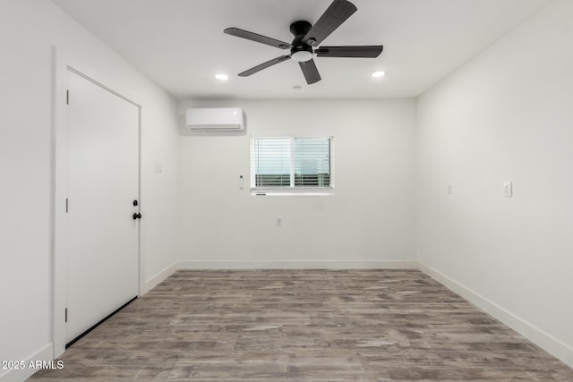 unfurnished room featuring an AC wall unit, light hardwood / wood-style flooring, and ceiling fan