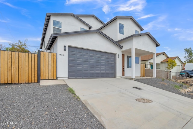 view of front facade with stucco siding, fence, concrete driveway, and a gate