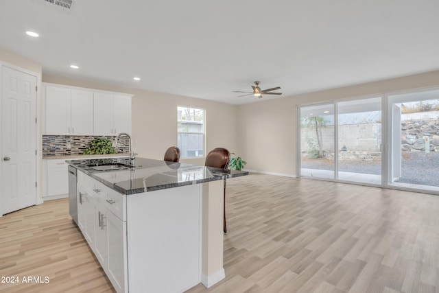 kitchen featuring backsplash, open floor plan, dishwasher, dark stone counters, and a sink