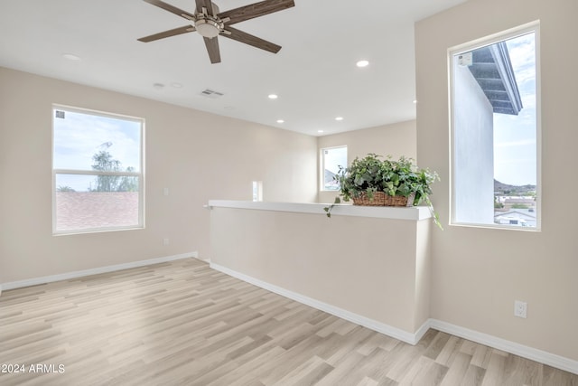 empty room featuring a wealth of natural light, ceiling fan, and light wood-type flooring