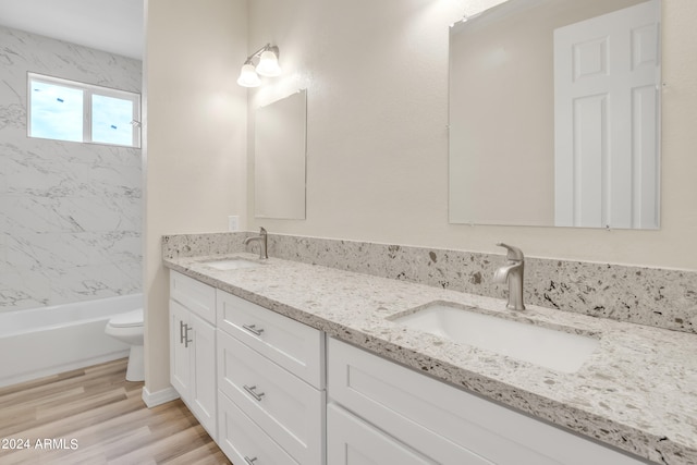 full bathroom featuring double vanity, wood finished floors, toilet, and a sink