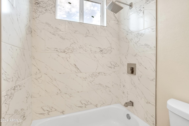 bathroom with toilet and tiled shower / bath combo