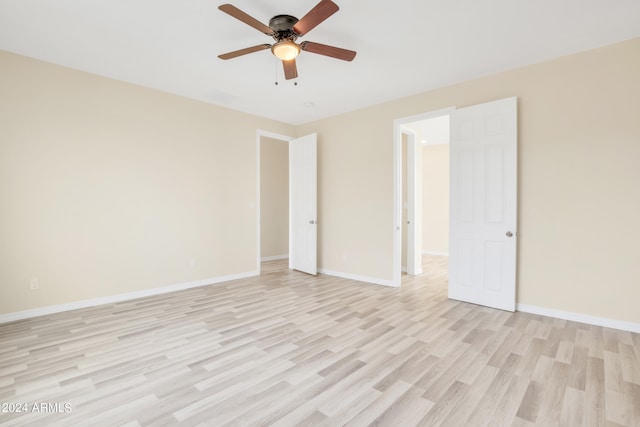 empty room featuring a ceiling fan, baseboards, and light wood-type flooring