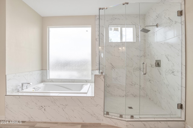 bathroom featuring a bath and a marble finish shower