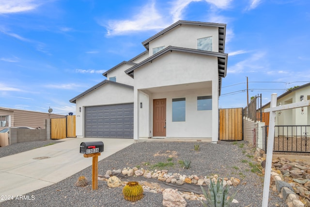 view of front of house with concrete driveway, fence, a garage, and stucco siding