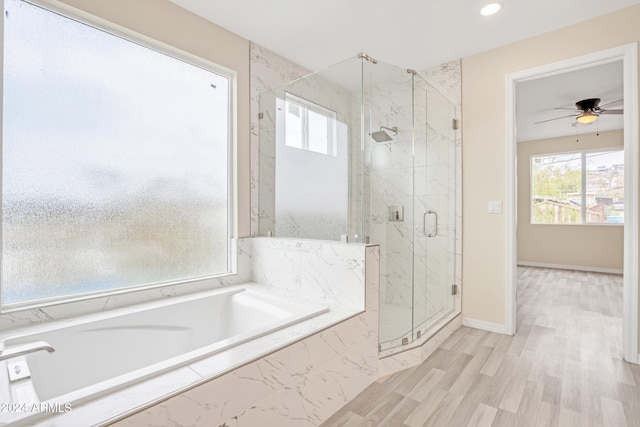 bathroom featuring a marble finish shower, baseboards, a garden tub, and a healthy amount of sunlight