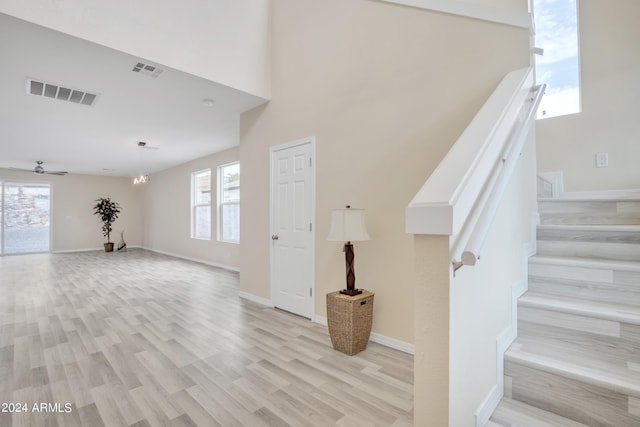 staircase featuring a high ceiling, hardwood / wood-style floors, and ceiling fan