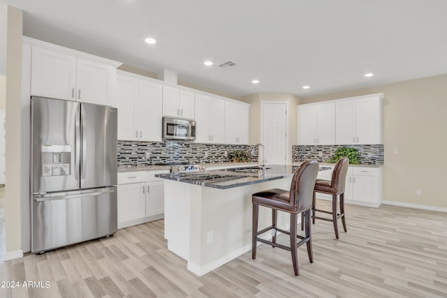 kitchen with visible vents, a sink, white cabinetry, appliances with stainless steel finishes, and a breakfast bar area